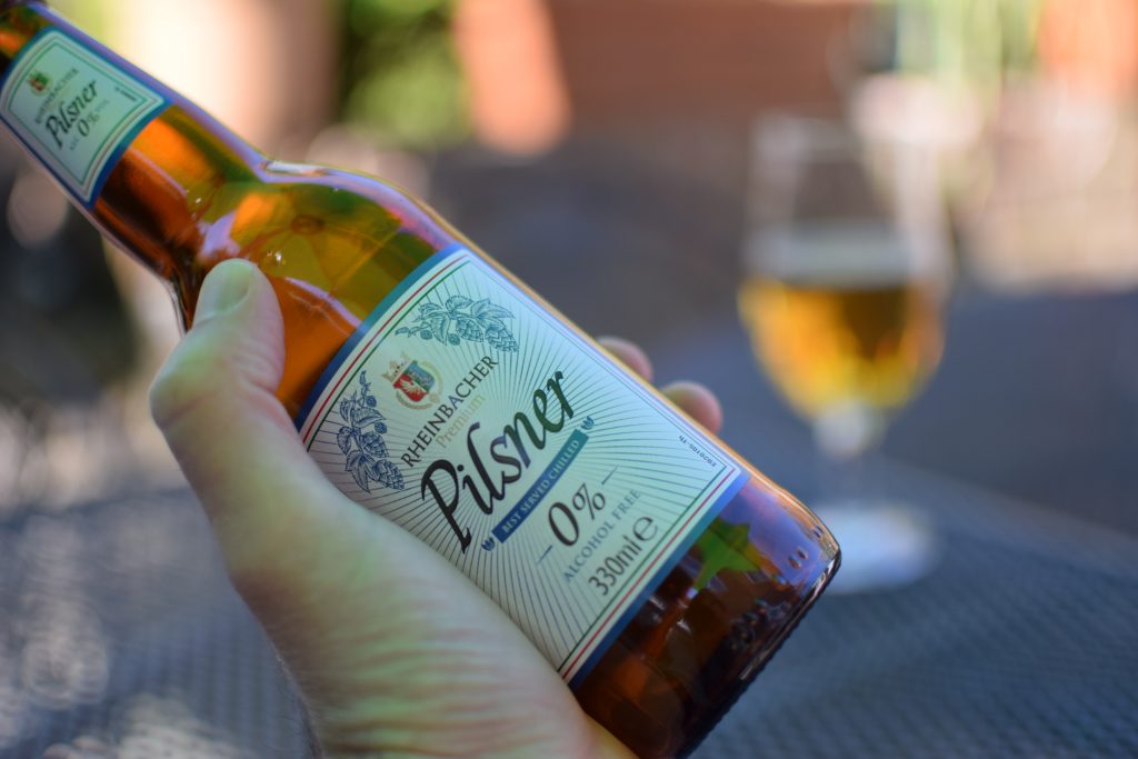 Rheinbacker Pilsner Aldi 0% beer with glass in background